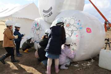 牧草ロールに絵を描く児童たち